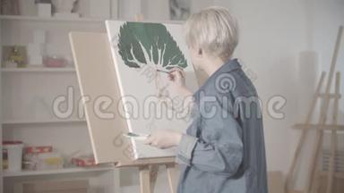 一个年轻的金发女人用颜料画树